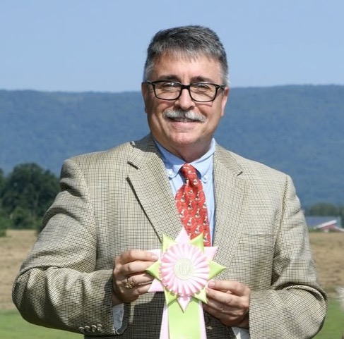 Jerome Elliott holding a show-ring ribbon outdoors.